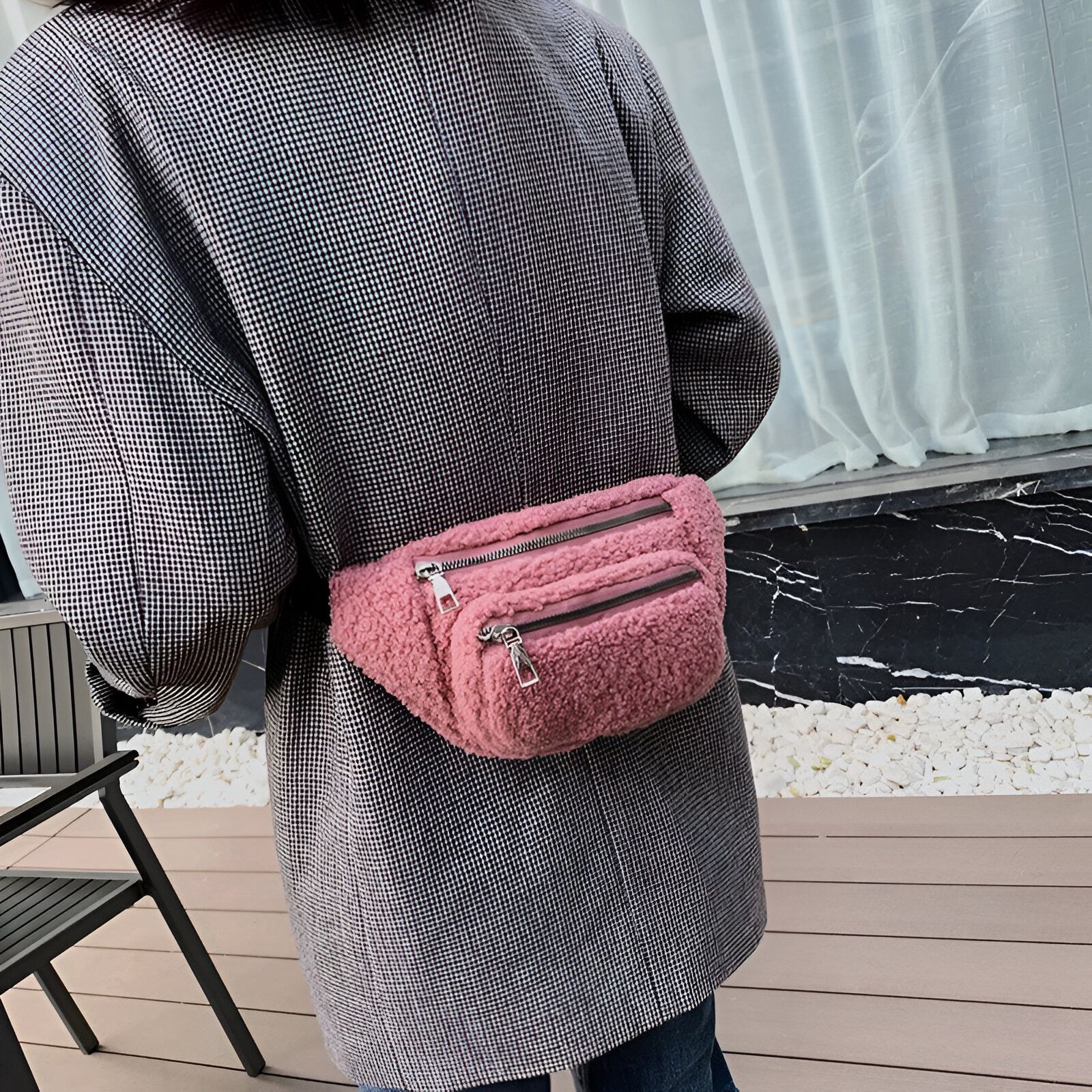 Une femme portant un sac banane rose en fourrure.