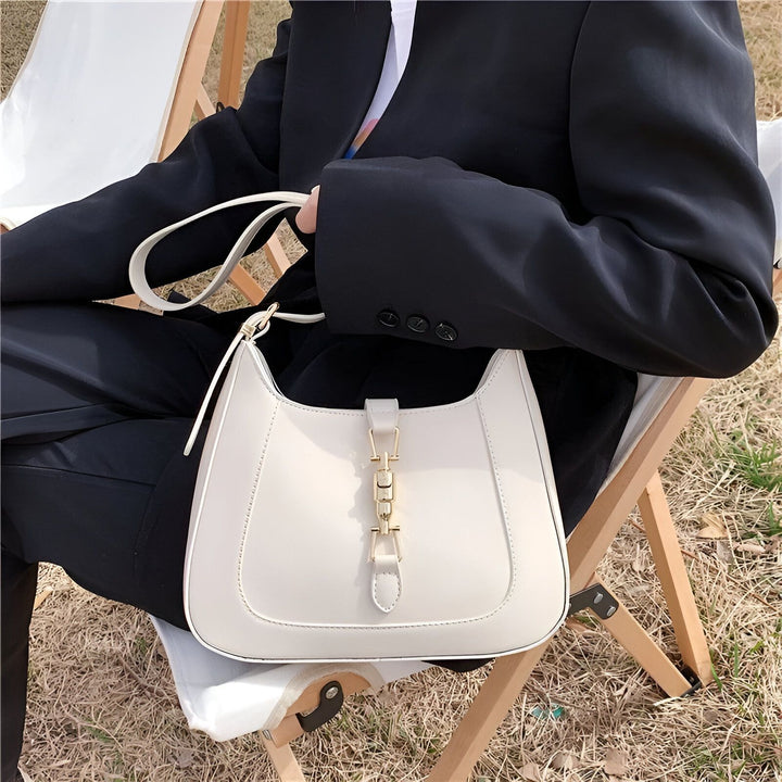 Sac blanc à bandoulière avec fermoir doré, tenu par une personne en blazer noir., 46193934565600,46193934598368,46193934631136,46193934663904,46193934696672