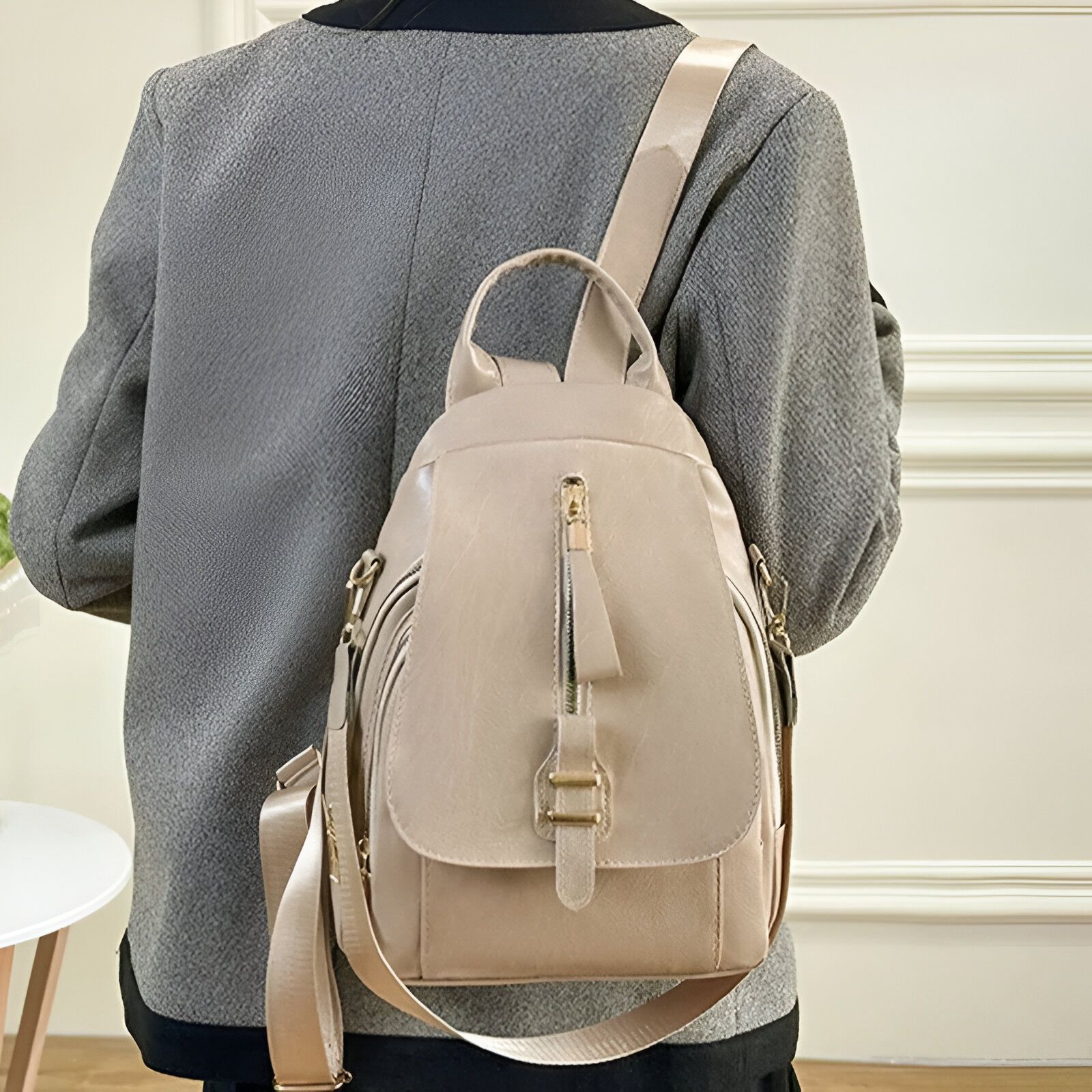 Sac à dos en cuir beige porté par une femme.