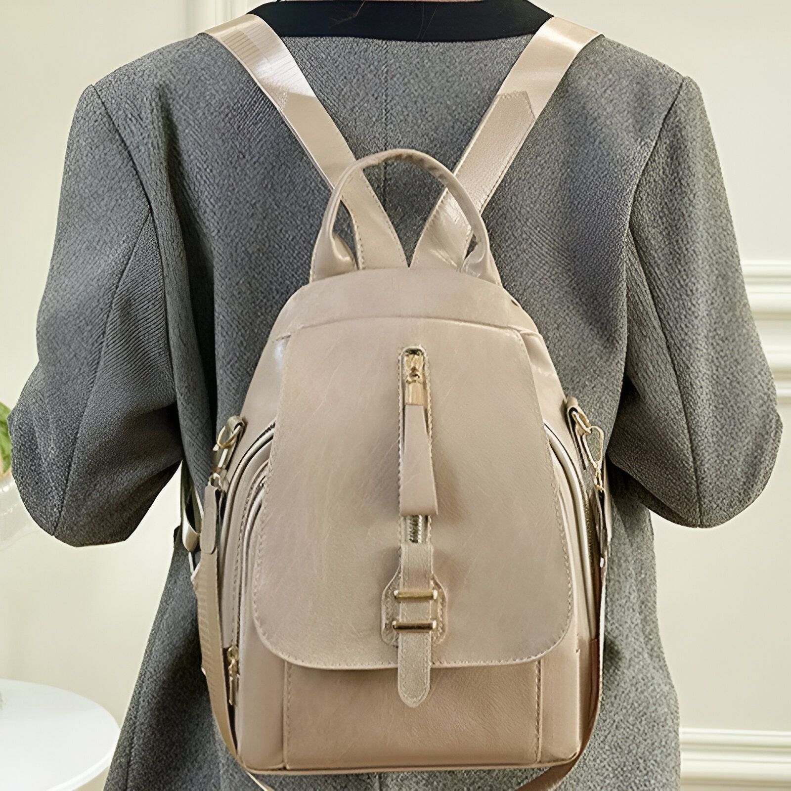 Un sac à dos beige en cuir porté par une femme.