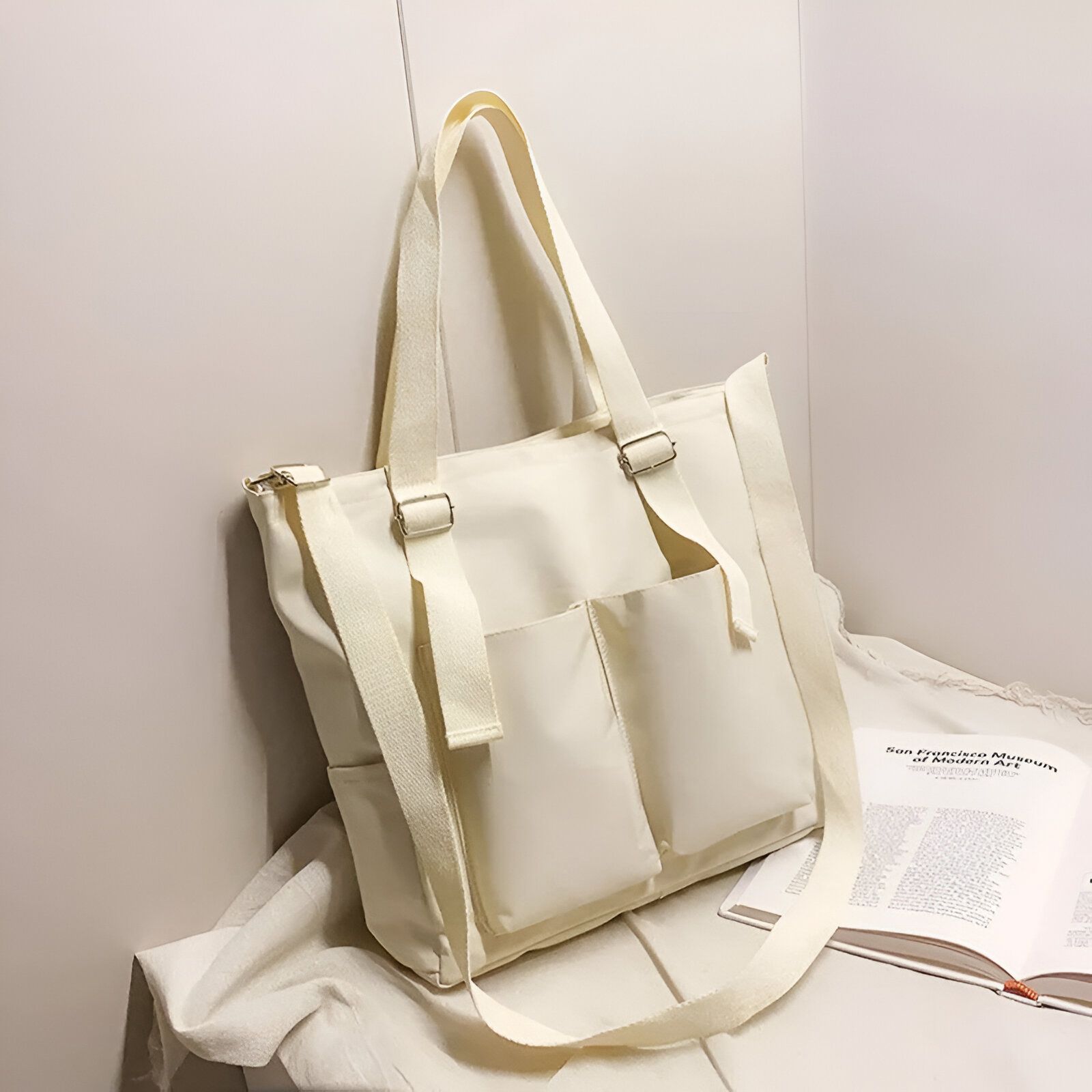 Un grand sac à main en toile beige avec deux poches sur le devant et une longue sangle.