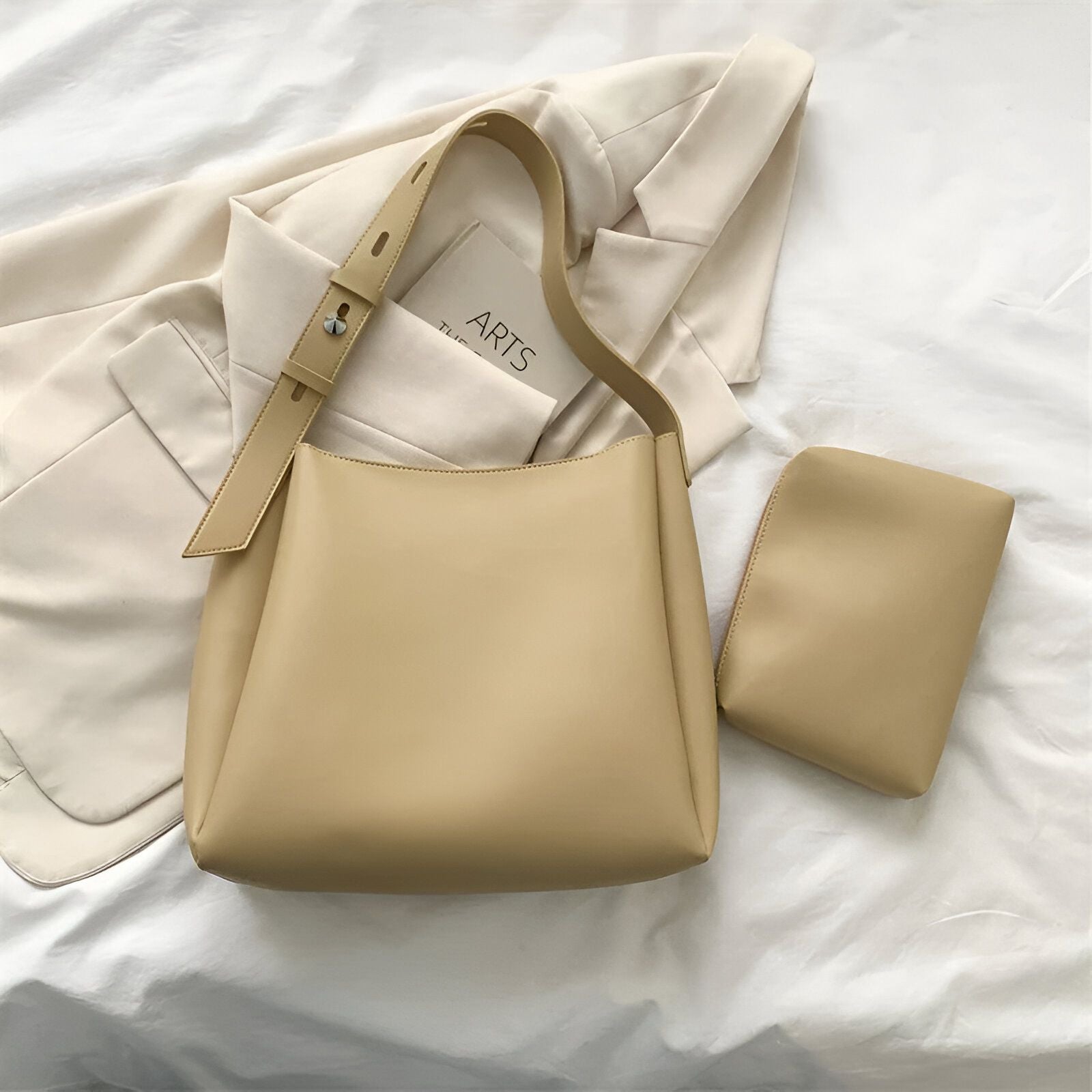 Un sac à main beige avec une petite pochette assortie sur un fond blanc.