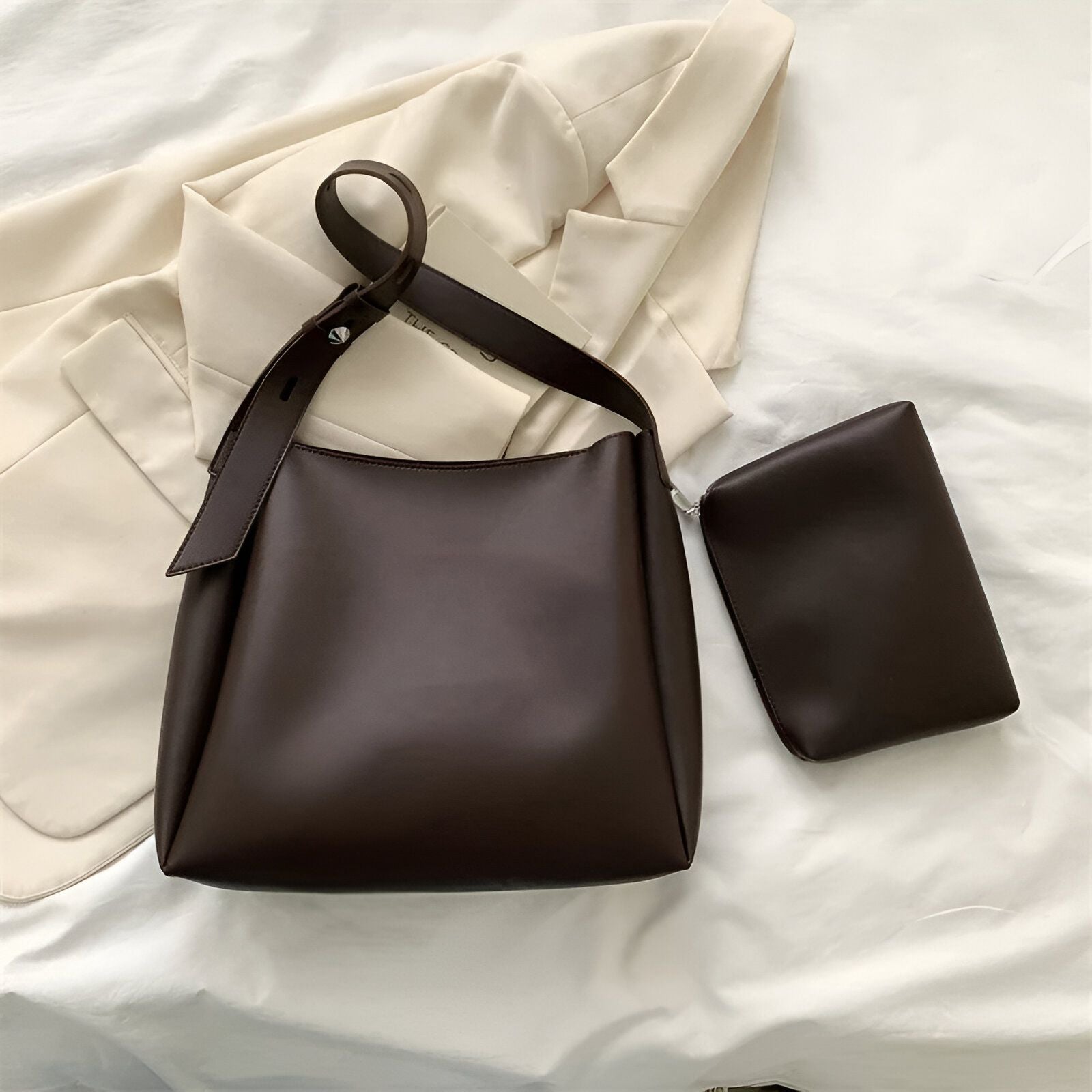 Un grand sac à main brun en cuir avec une petite pochette assortie.