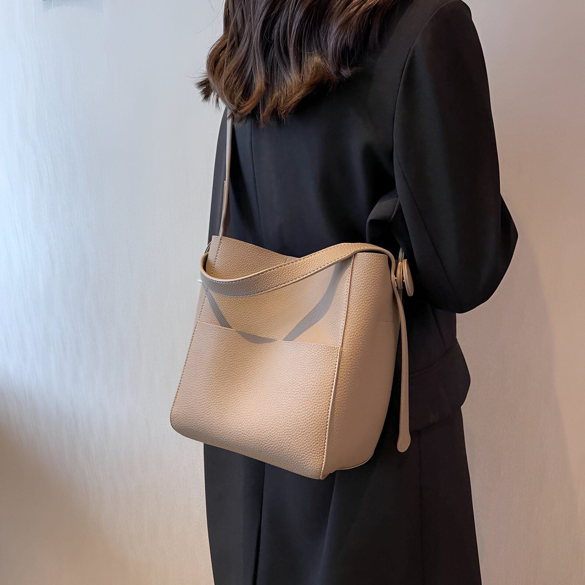 Une femme portant un sac à main beige en cuir.