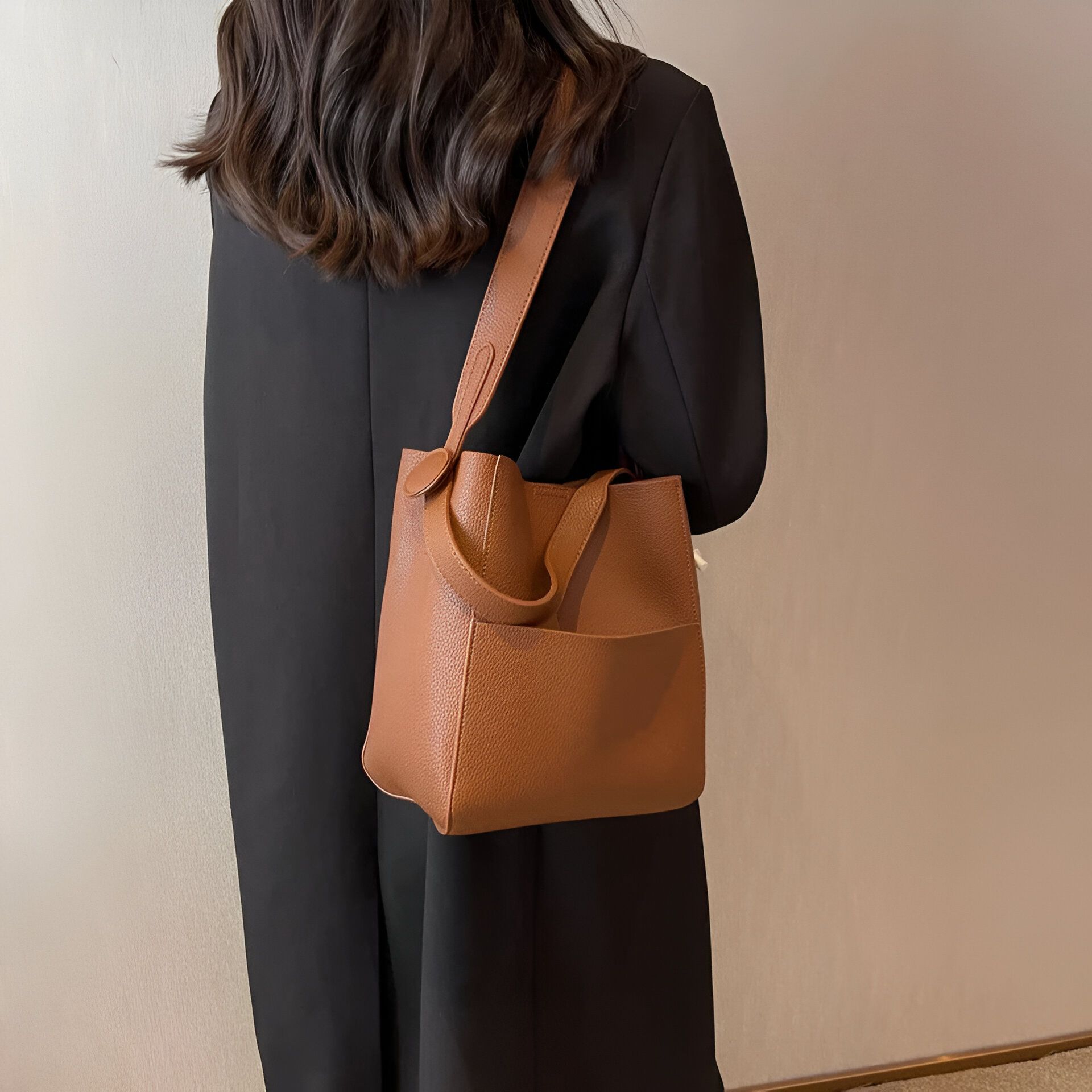 Une femme portant un sac à main brun en cuir sur l'épaule.