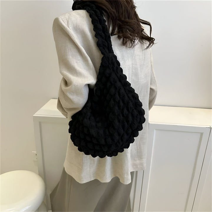 Sac à bandoulière noir texturé porté sur l'épaule avec un blazer clair., 46193876599008,46193876631776,46193876664544,46193876697312,46193876730080