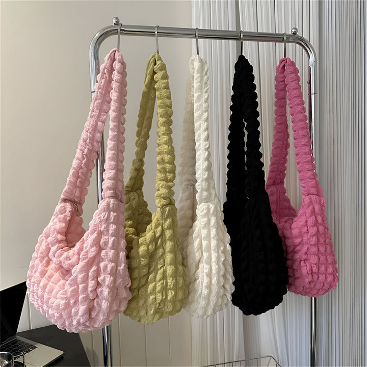 Plusieurs sacs texturés de couleurs variées (rose, vert, blanc, noir, fuchsia) suspendus sur un portant., 46193876599008,46193876631776,46193876664544,46193876697312,46193876730080