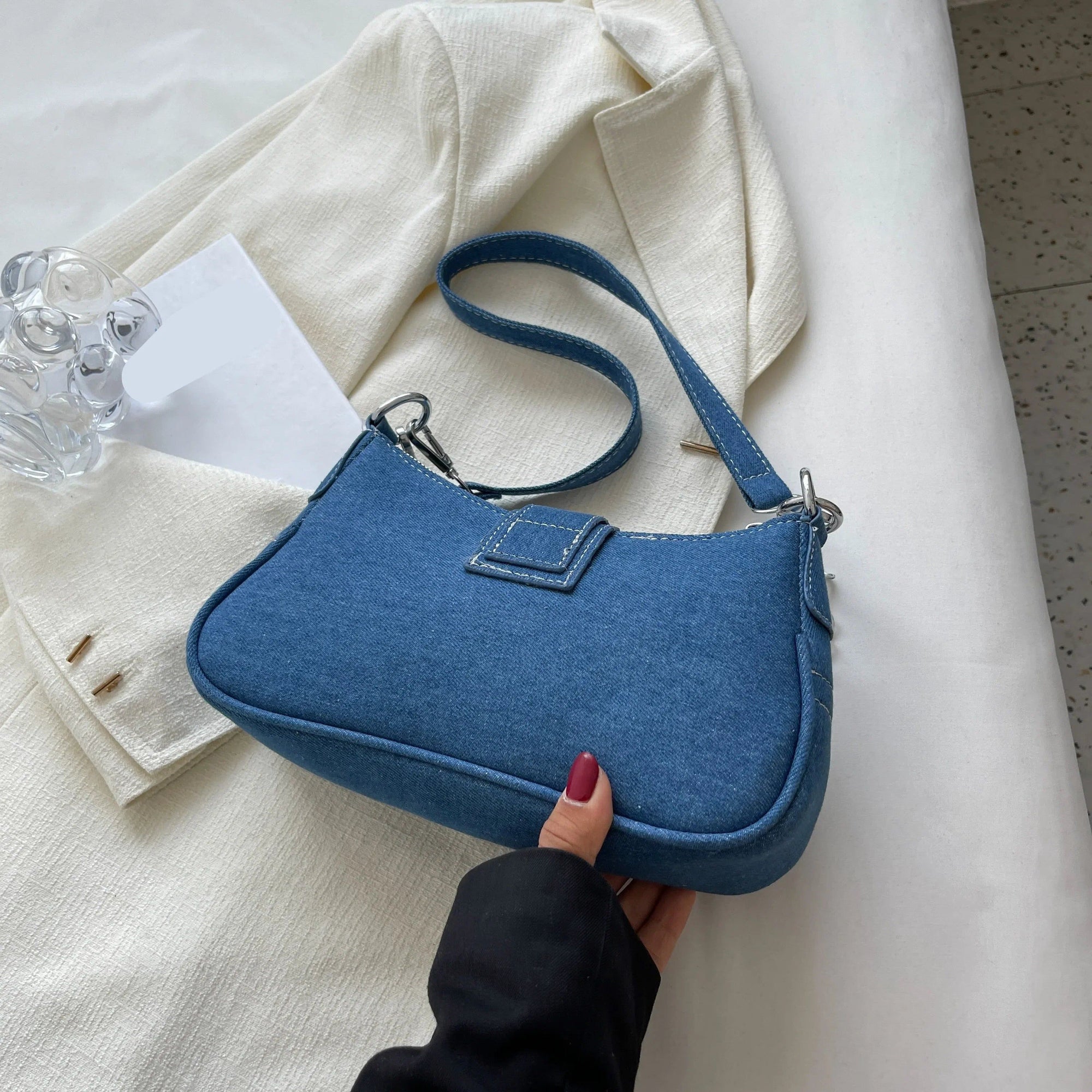 Un sac à main en jean bleu sur une surface blanche.