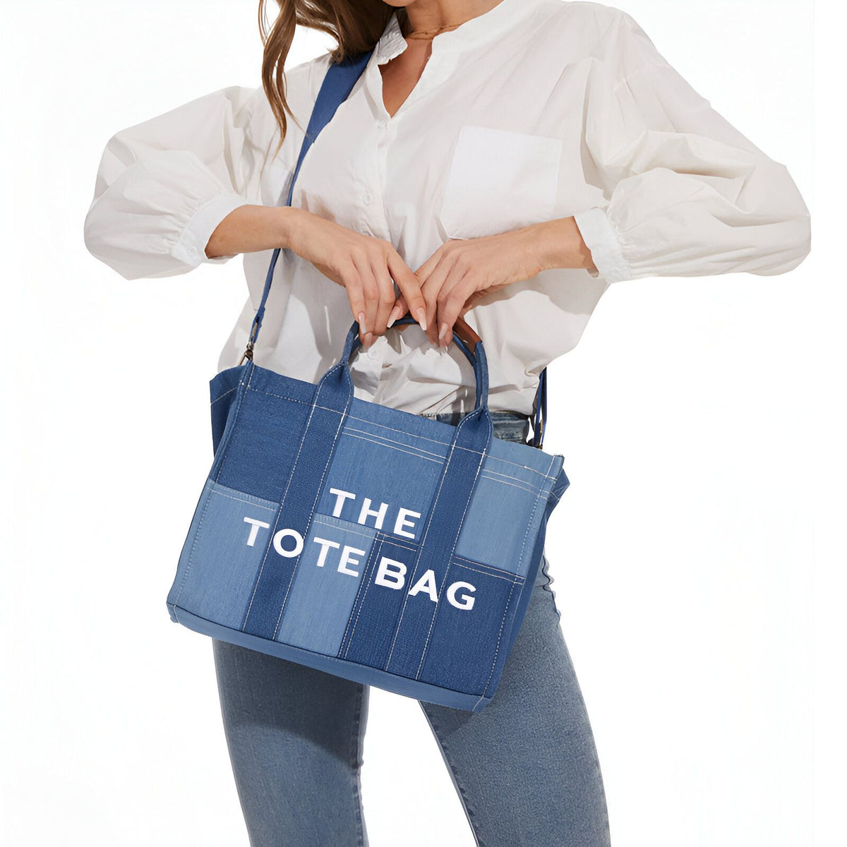 Une femme portant un sac à main en jean bleu avec l&#39;inscription &quot;The Tote Bag&quot; en blanc.