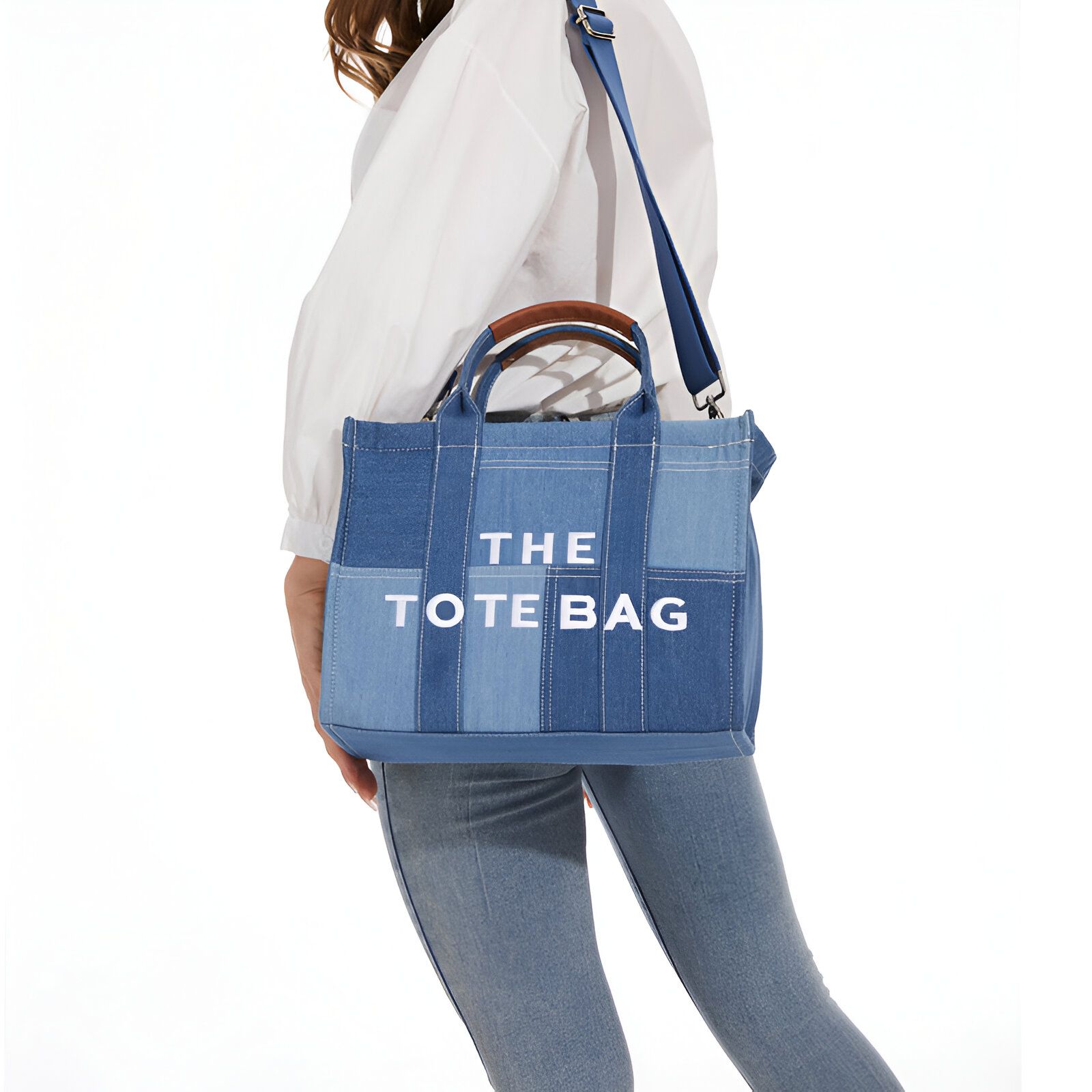 Une femme portant un sac à main en denim bleu avec l'inscription "THE TOTE BAG" en blanc.