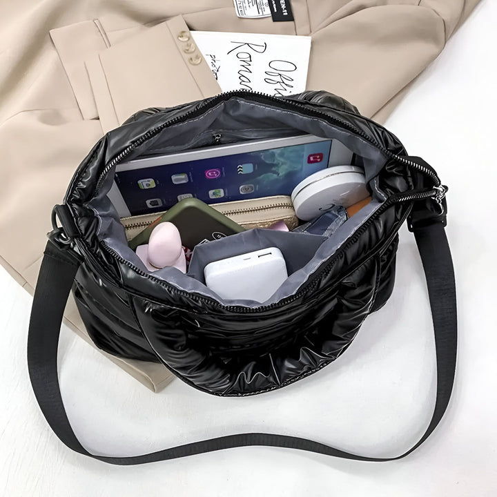 Sac noir matelassé ouvert montrant son contenu : tablette, batterie externe et autres objets., 46193876926688,46193876959456,46193876992224,46193877024992,46193877057760