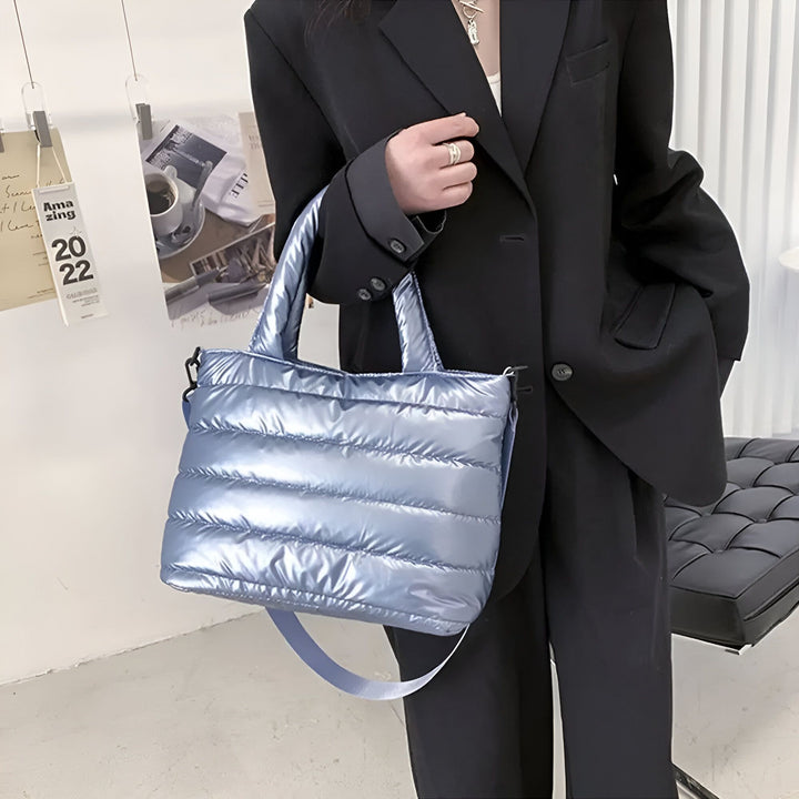 Personne tenant un sac bleu matelassé brillant., 46193876926688,46193876959456,46193876992224,46193877024992,46193877057760