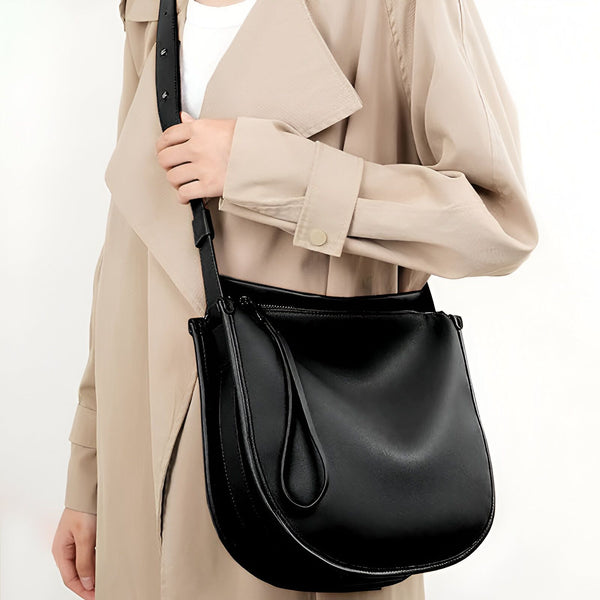 Sac à bandoulière noir en cuir porté avec un trench coat beige., 46193866113248