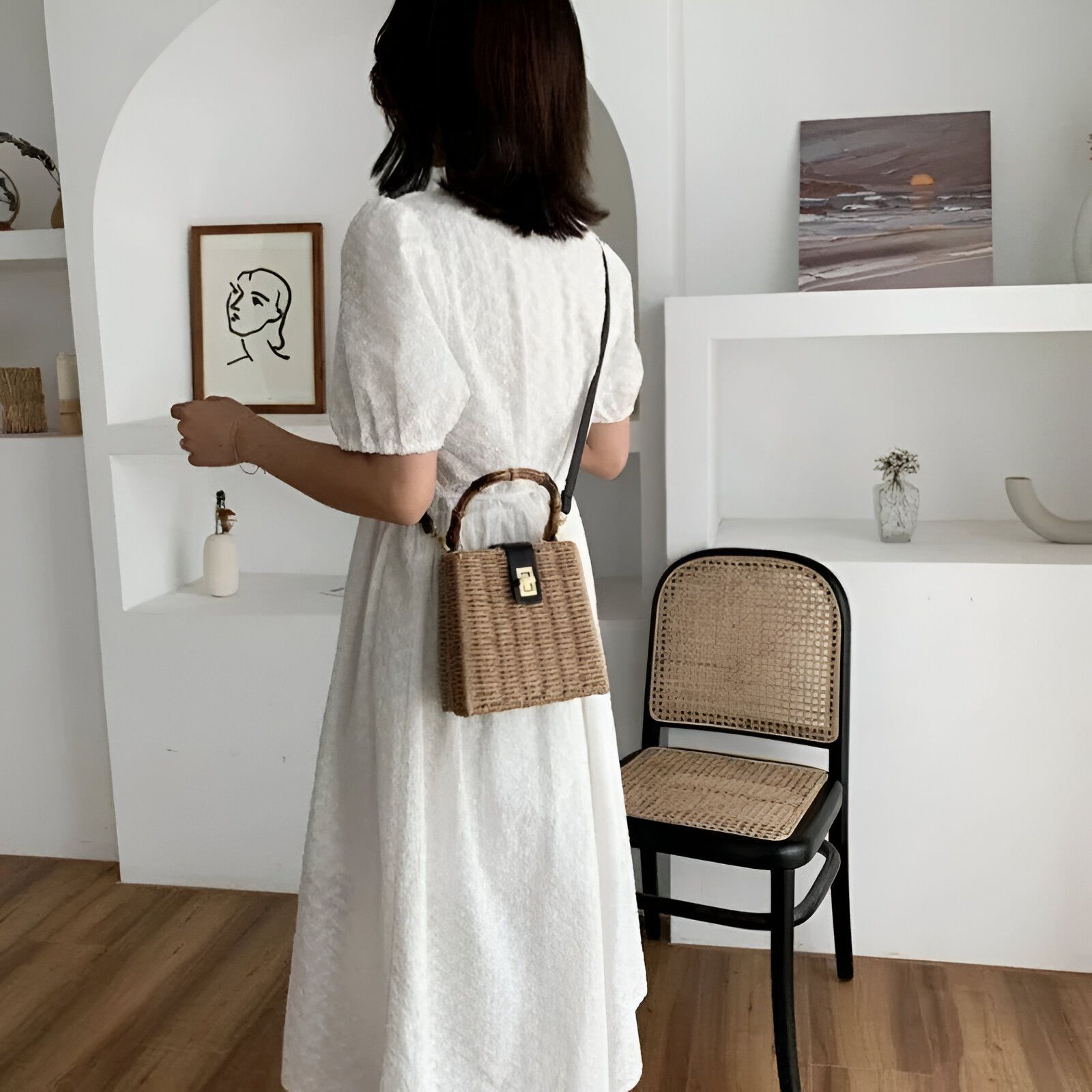 Une femme portant une robe blanche et un sac à main en osier.