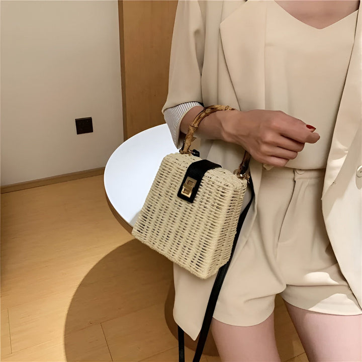 Femme avec un sac en paille rectangulaire à anses bambou et sangle noire, vêtue d'un tailleur beige., 46193945510112,46193945542880
