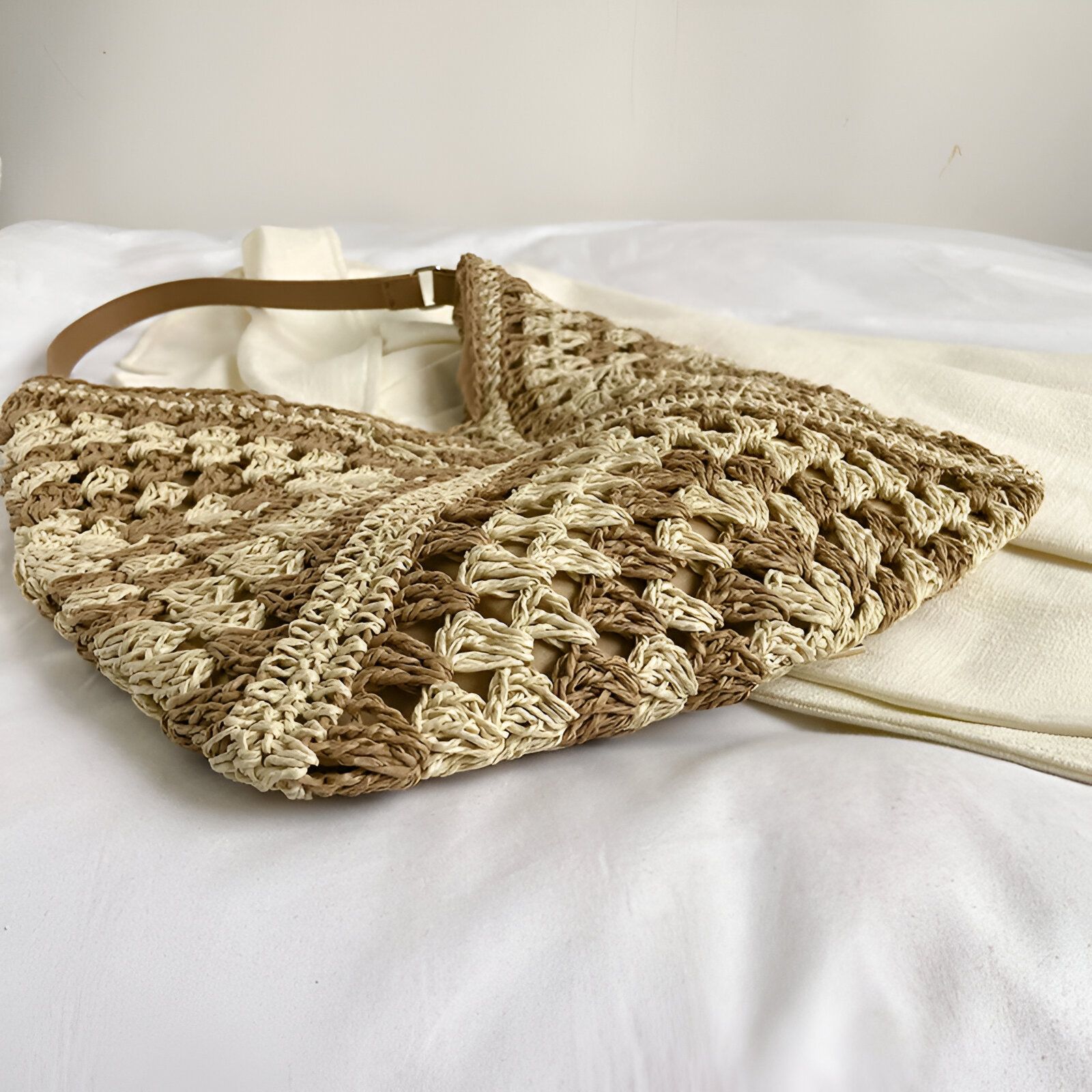 Un sac à main en paille beige et marron posé sur un tissu blanc.