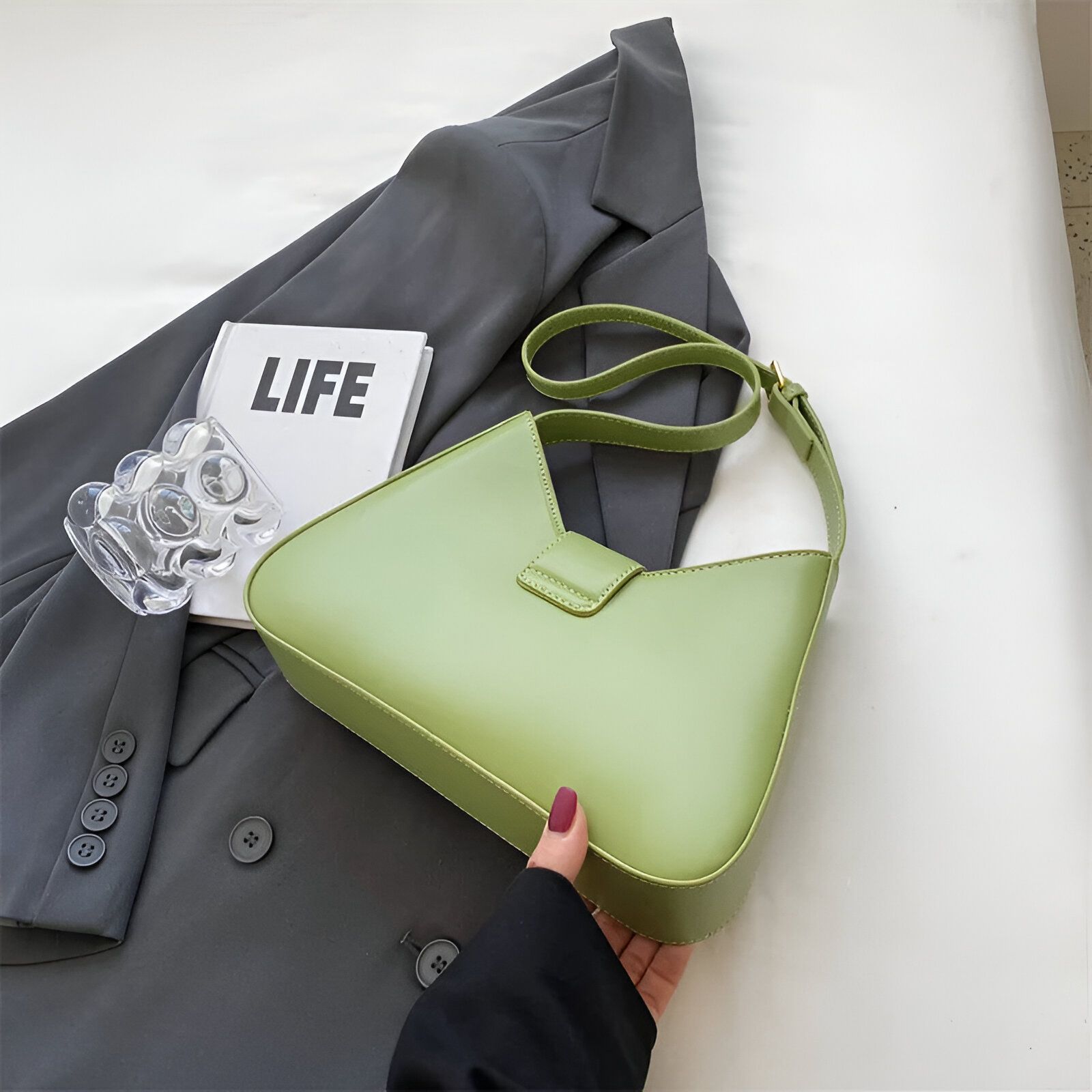 Un sac à main vert clair sur un blazer gris.