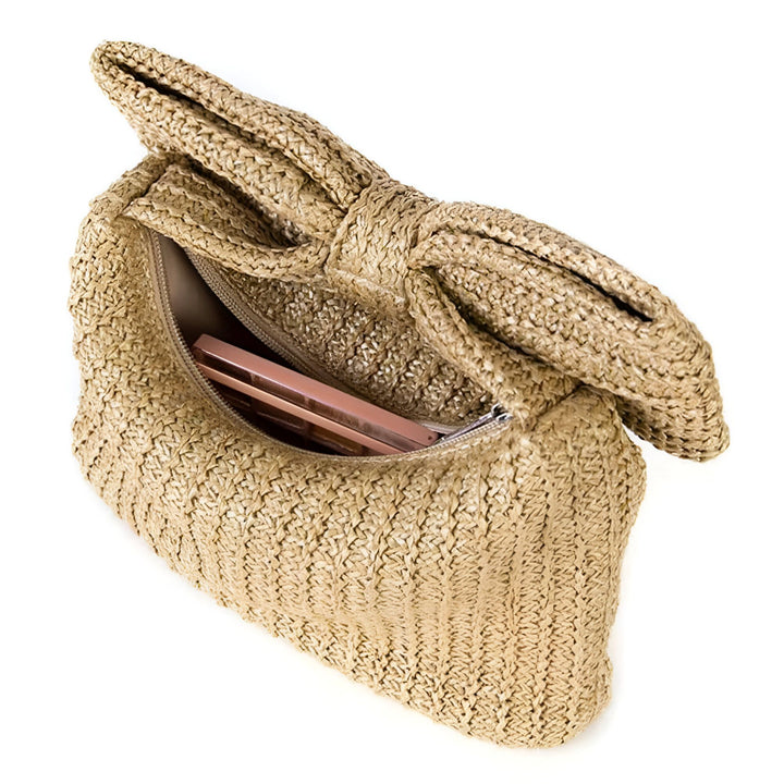 Pochette en paille beige nouée, ouverte, un objet rose à l'intérieur., 46194021794016