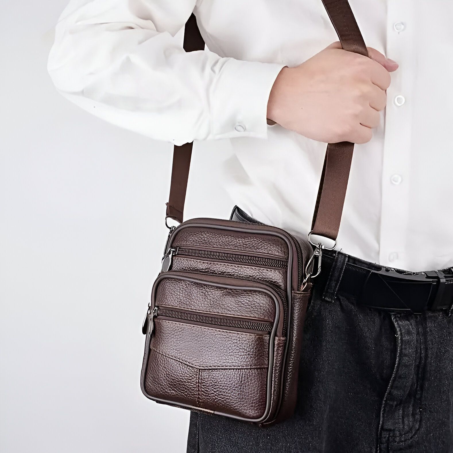 Un homme portant un sac à bandoulière en cuir marron.