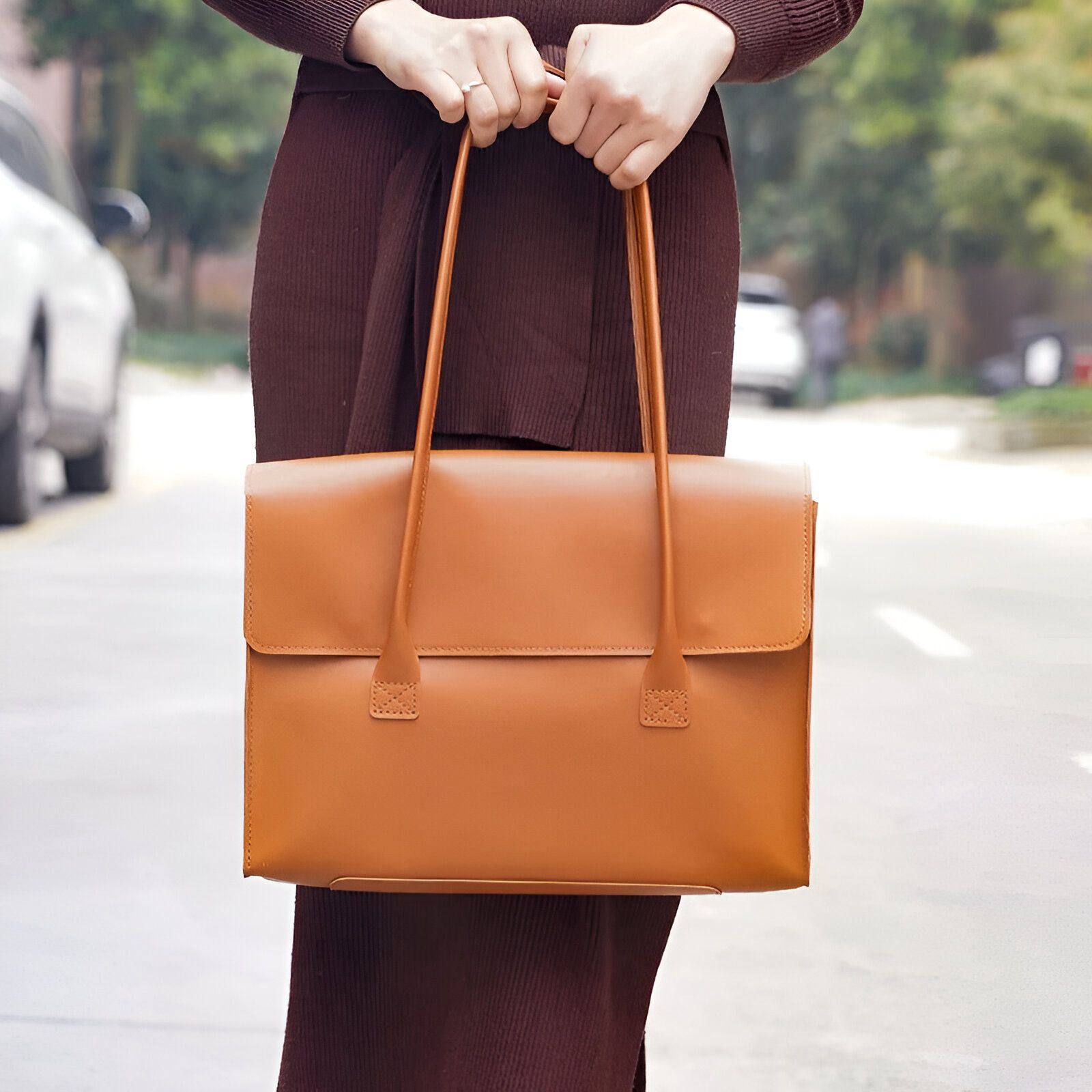 Une femme porte un sac à main brun en cuir.