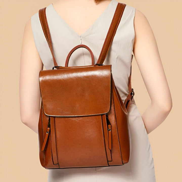 Sac à dos en cuir marron avec rabat et fermetures éclair porté par une personne de dos., 46193898586336,46193898619104,46193898651872