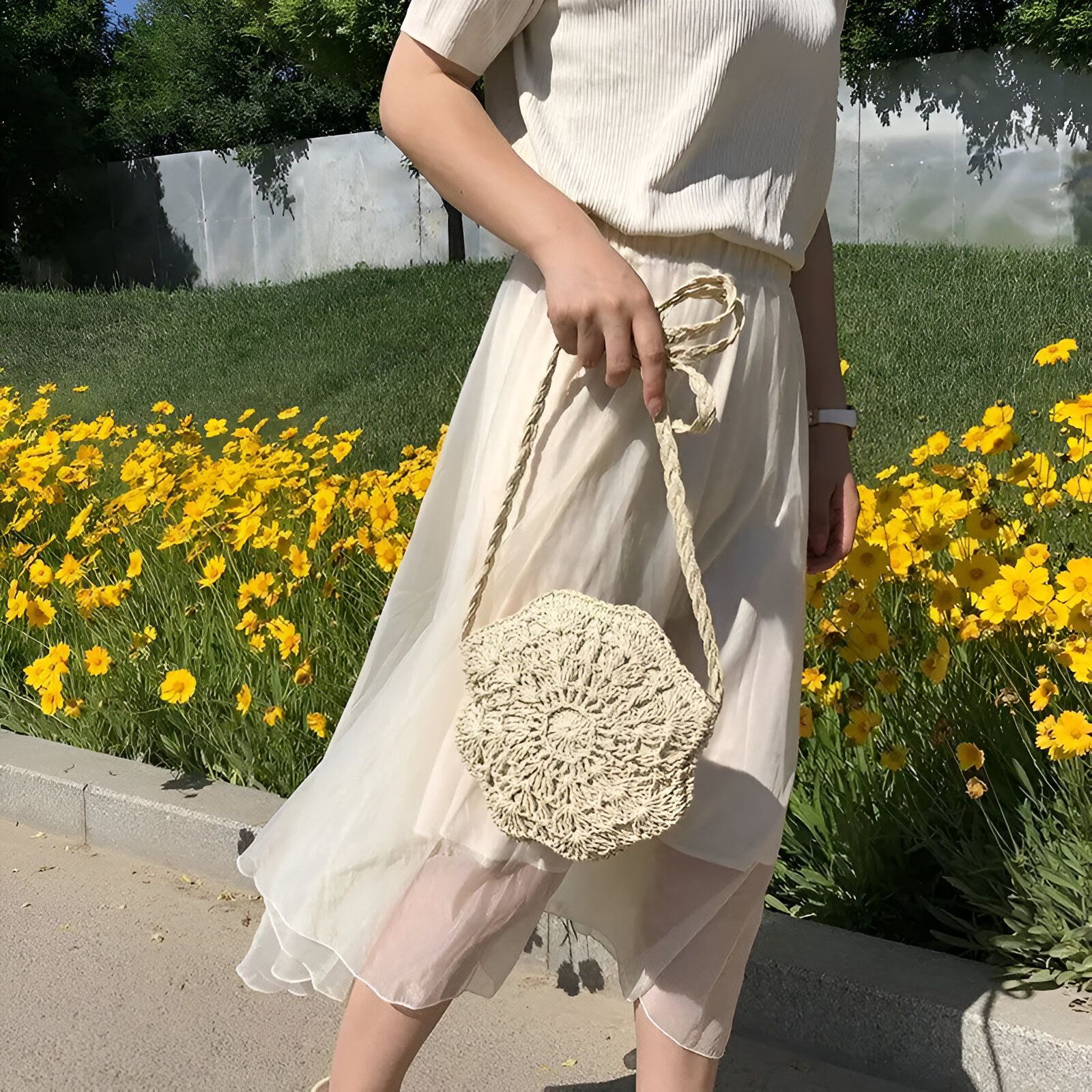 Une femme portant une robe blanche et un sac à main en osier rond.