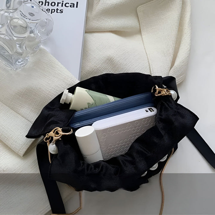 Intérieur d'un sac noir élégant chaîne or perle, contenant crème, téléphone, power bank, rouge à lèvres., 46194007572704