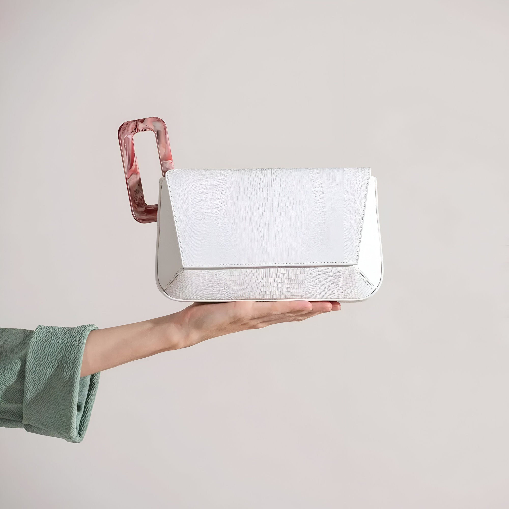 Un sac à main blanc avec une poignée en plastique rouge et blanc est tenu dans une main.