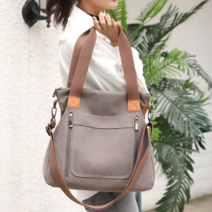 Sac fourre-tout en toile gris porté par une femme, avec poches zippées et bretelles marron., 46193891836128,46193891901664,46193891934432,46193891967200,46193891999968