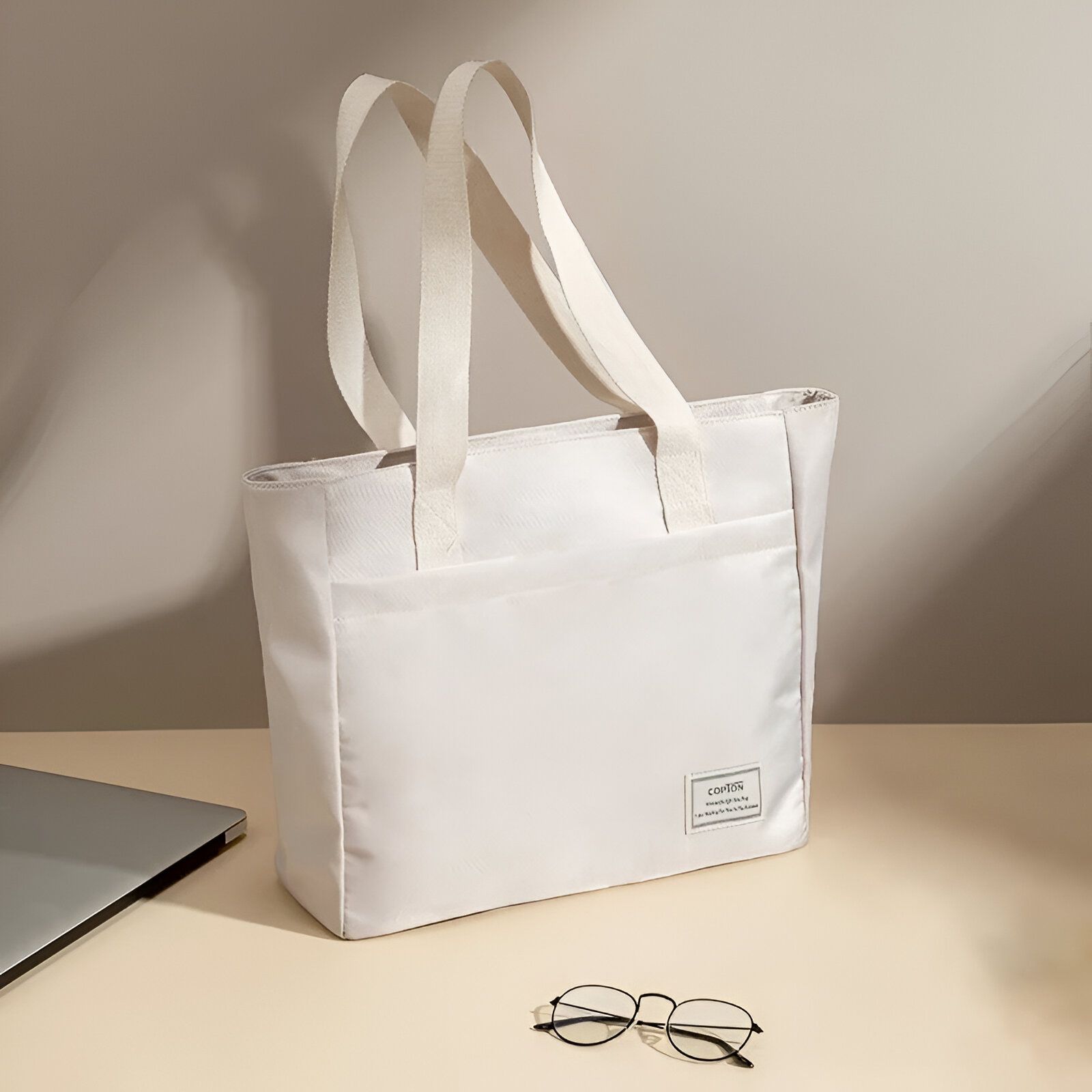 Sac à main blanc sur fond beige avec des lunettes sur le côté.