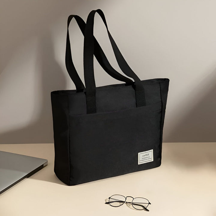 Sac cabas noir sur un bureau, près d'un ordinateur portable et de lunettes., 46193955471584,46193955504352,46193955537120