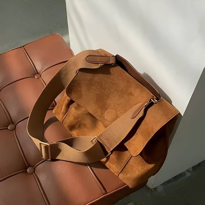 Sac bandoulière en daim marron posé sur un ottoman en cuir., 46193886396640,46193886429408