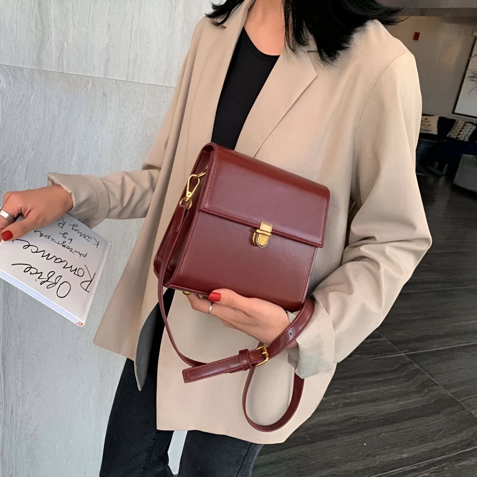 Une femme portant un blazer beige et un sac à bandoulière marron foncé.