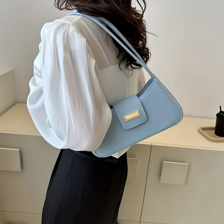 Sac baguette bleu clair avec fermoir doré, porté à l'épaule par une personne., 46193943445728,46193943478496,46193943511264,46193943544032,46193943576800,46193943609568