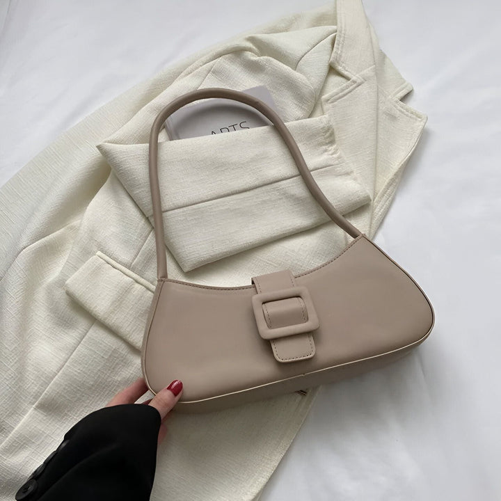 Sac à main baguette beige avec détail boucle, posé sur veste blanche., 46193943707872,46193943740640,46193943773408,46193943806176