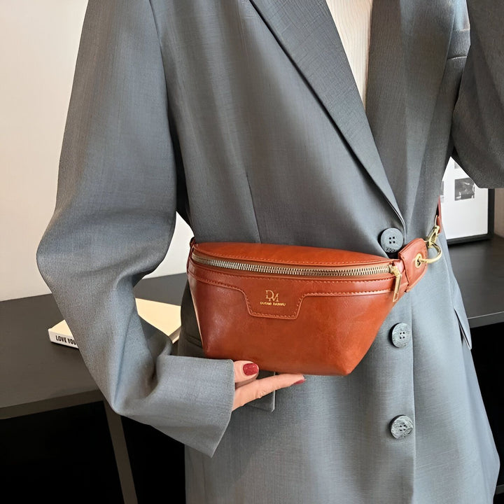 Sac banane en cuir marron porté sur une veste grise., 46194025332960,46194025365728,46194025398496,46194025431264,46194025464032