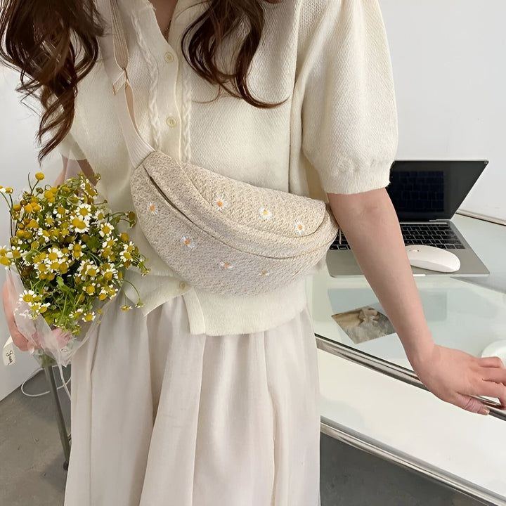 Femme portant un sac banane beige à broderie marguerites et tenant un bouquet de fleurs sauvages., 46194023301344,46194023334112