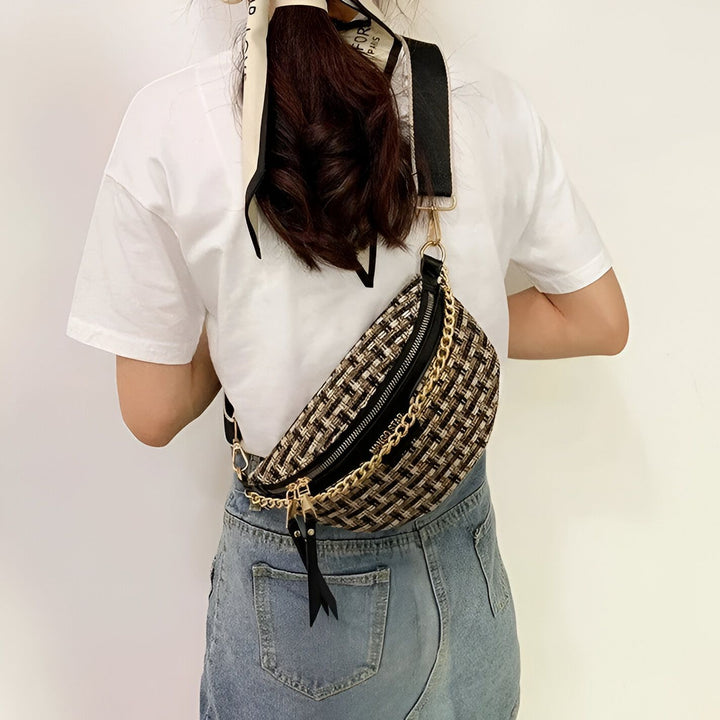 Vue de dos d'une personne portant un sac banane tissé beige/noir avec zip et chaîne dorés., 46194025005280,46194025038048,46194025070816,46194025103584
