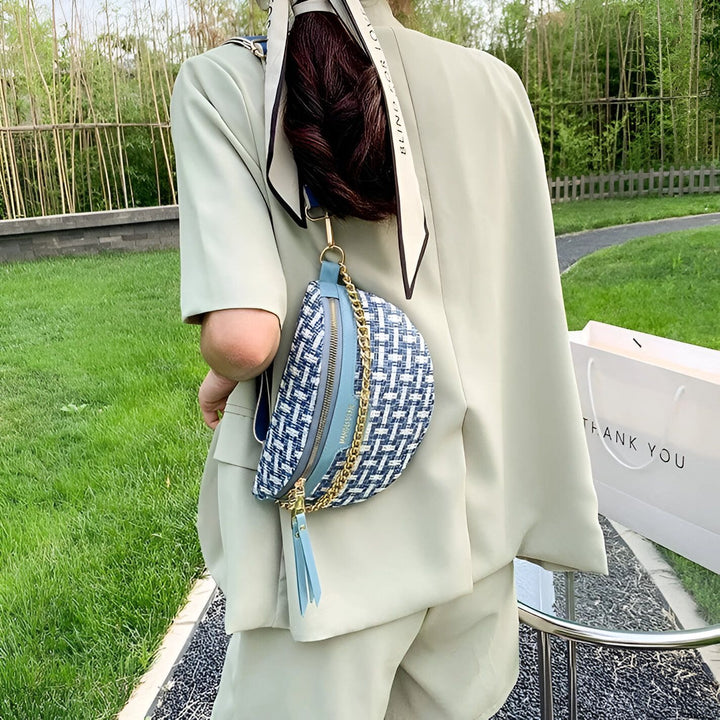Sac banane bleu et blanc à motif tressé et chaîne dorée porté par une personne en costume vert., 46194025005280,46194025038048,46194025070816,46194025103584