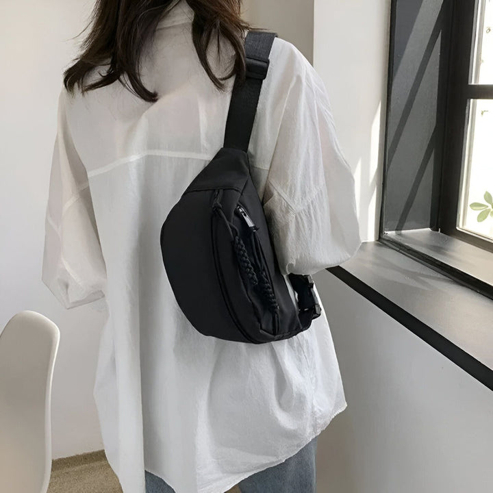 Sac banane noir porté en bandoulière par une personne en chemise blanche., 46194024710368,46194024743136,46194024775904,46194024808672