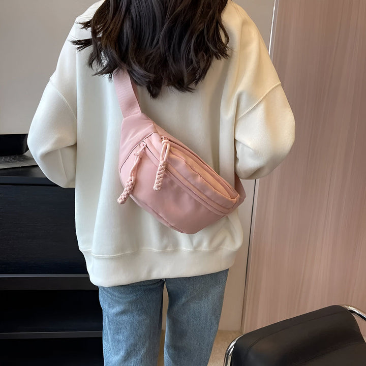 Une personne porte un sweat blanc, un jean et une banane rose dans le dos., 46194024710368,46194024743136,46194024775904,46194024808672