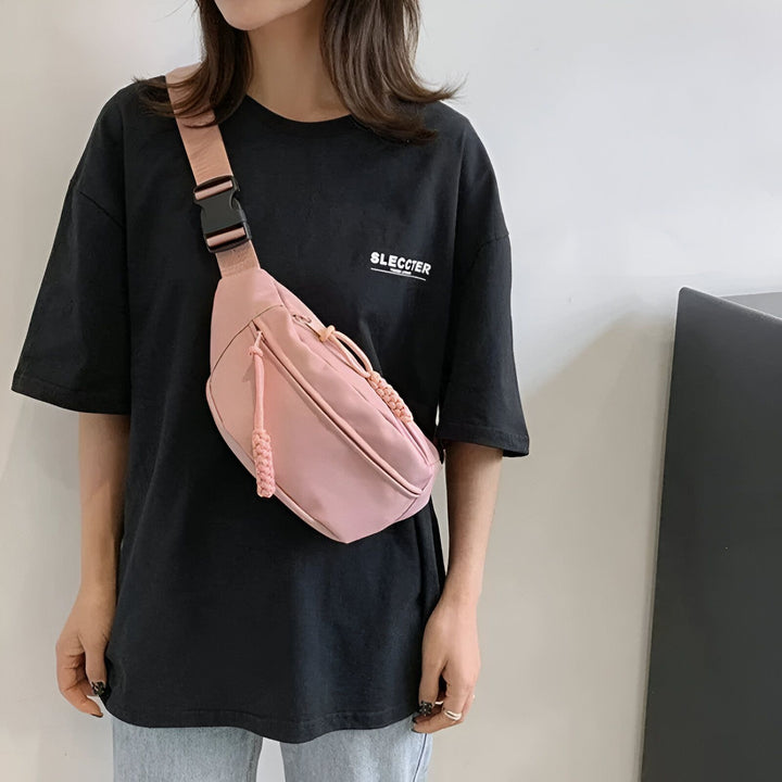 Personne portant un sac banane rose en bandoulière avec un t-shirt noir., 46194024710368,46194024743136,46194024775904,46194024808672