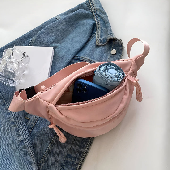 Sac banane rose ouvert avec téléphone bleu et parapluie pliant sur une veste en jean., 46194024710368,46194024743136,46194024775904,46194024808672