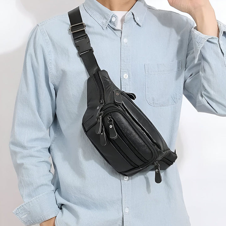 Sac banane noir en cuir porté en bandoulière par un homme en chemise bleue., 46194063802592,46194063835360,46194063868128