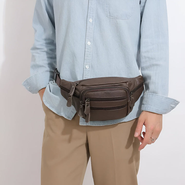 Sac banane en cuir marron porté sur chemise bleu clair et pantalon kaki., 46194063802592,46194063835360,46194063868128