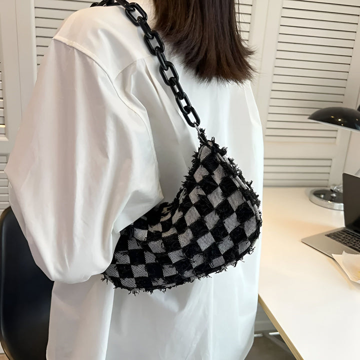 Sac à bandoulière à damier noir et blanc avec chaîne noire porté sur une chemise blanche., 46193995612384,46193995645152
