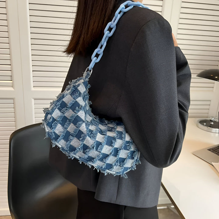Sac à main en jean bleu à motif damier avec chaîne bleue porté sur l'épaule., 46193995612384,46193995645152