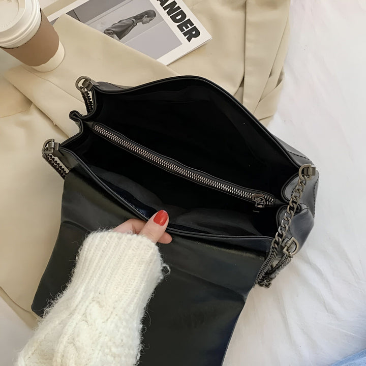 Vue de l'intérieur d'un sac à main noir ouvert, une main en pull blanc tenant le rabat., 46193950523616,46193950556384