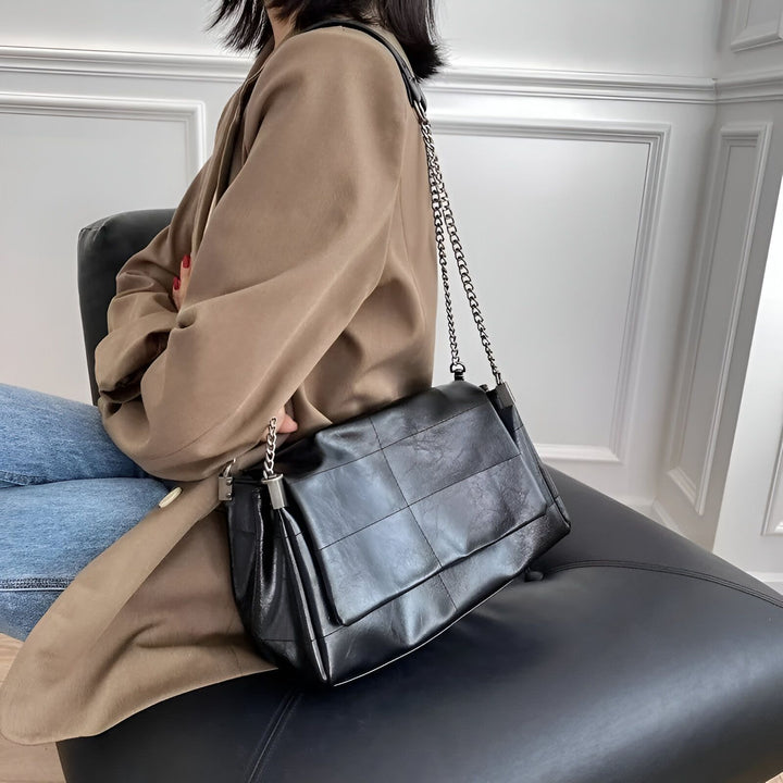 Sac à main en cuir noir motif carré porté par une femme en manteau beige., 46193950523616,46193950556384
