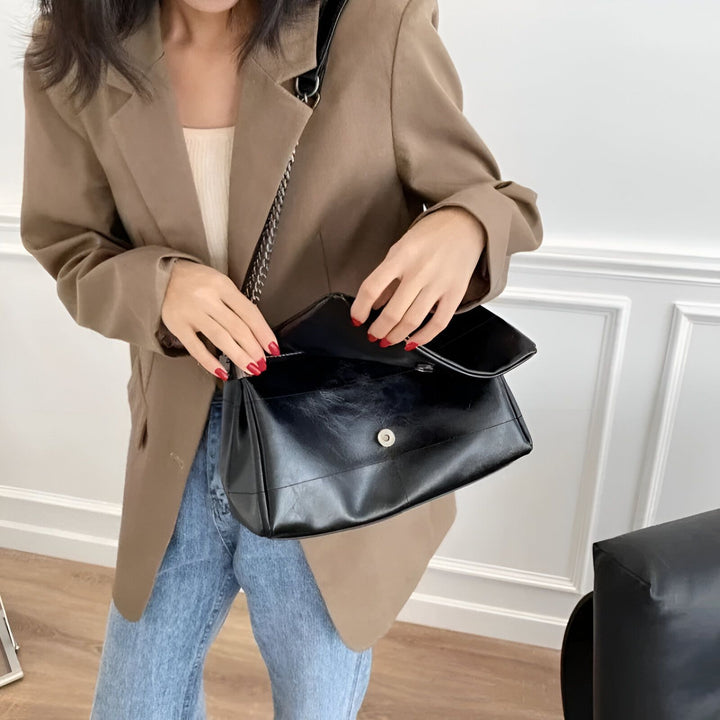 Femme en blazer marron et jean ouvrant un sac à main noir à bandoulière chaîne., 46193950523616,46193950556384